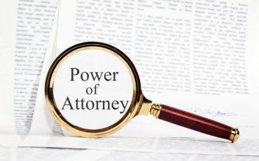 Power of Attorney Concept - paperwork representing a Power of Attorney, with a magnifying glass over, highlighting Power of Attorney.